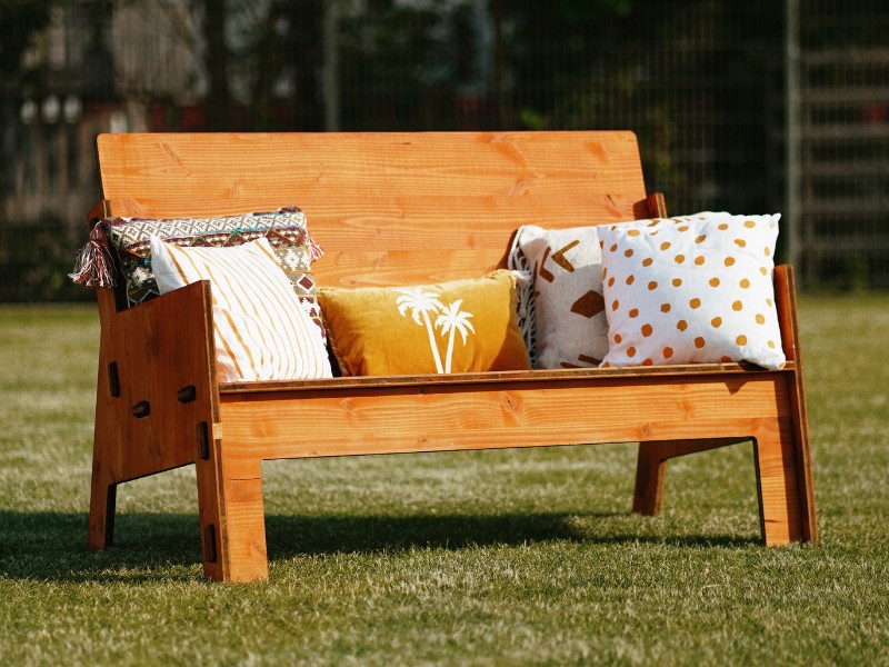 Gartenbank mit Auro-Holzlasur im Farbton "Lava" Gartenbank mit Kissen auf der Wiese mit Auro-Holzlasur in Orange (Farbton Lava) gestrichen