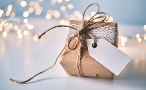 Kleines Päckchen mit Packpapier und Kordel mit Lichtern im Hintergrund