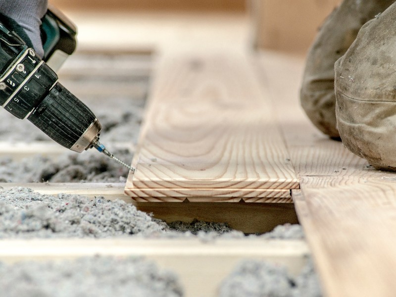 Die Zellulose-Einblasdämmung wird in die Unterkonstruktion des Fußbodens eingeblasen Eine Zellulose-Einblasdämmung isoliert von unten bevor der Fußboden verlegt wird